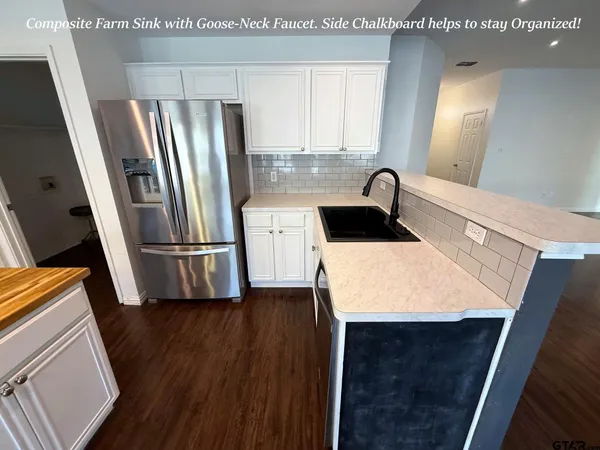 a kitchen with stainless steel appliances a refrigerator a sink a stove and white cabinets