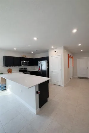 a view of kitchen with stainless steel appliances a sink of white cabinets and couches
