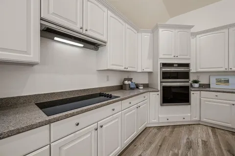 a kitchen with granite countertop white cabinets and stainless steel appliances
