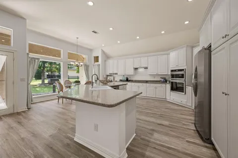 a kitchen with stainless steel appliances granite countertop a stove top oven a sink and a refrigerator