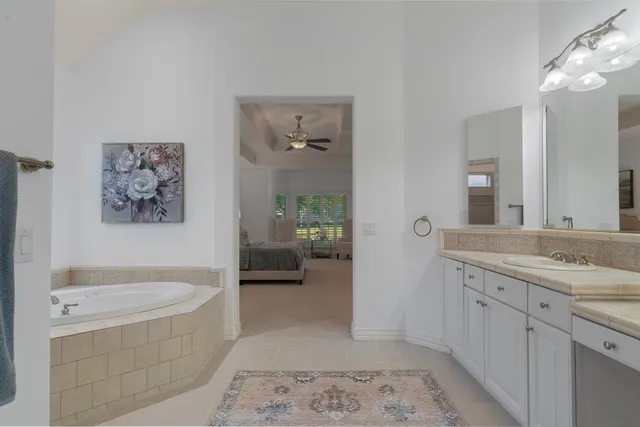 a spacious bathroom with a tub sink and mirror