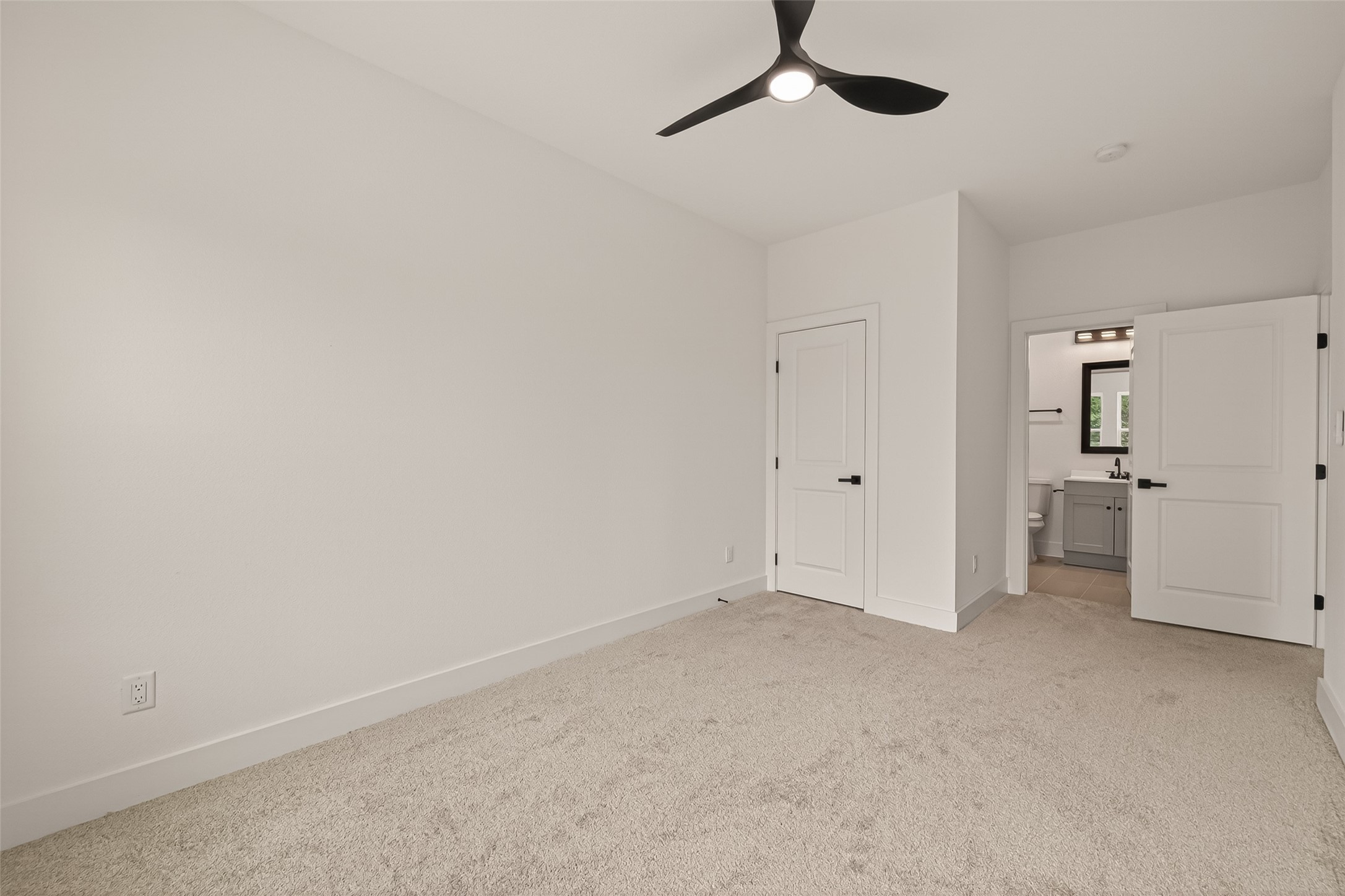 6808 Madrid Street Houston, TX 77021 - Photo 22 of 31 This bright bedroom features neutral walls and carpet, a modern ceiling fan, a closet, and an en-suite bathroom with sleek fixtures.