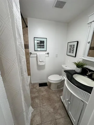 a white toilet sitting next to a white sink and vanity