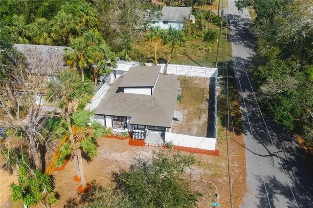 an aerial view of a house with swimming pool and large trees