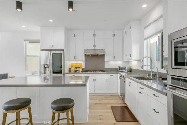 a kitchen with stainless steel appliances granite countertop a sink a stove a refrigerator cabinets and chairs