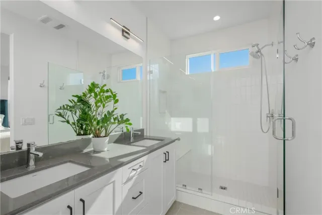 a bathroom with a granite countertop sink a mirror and shower