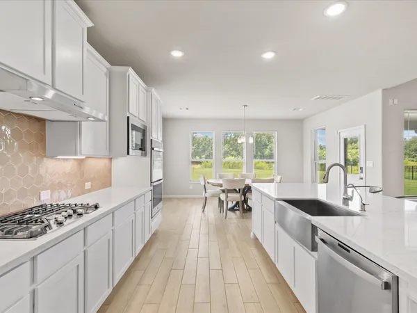 a large kitchen with stainless steel appliances a lot of counter space and a wooden floors