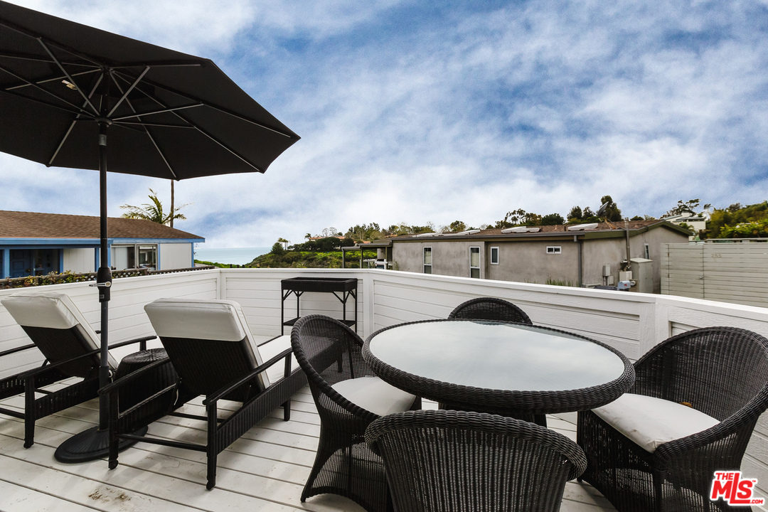 248 Paradise Cove Road Malibu, CA 90265 - Photo 23 of 35 a patio with a table and chairs under an umbrella