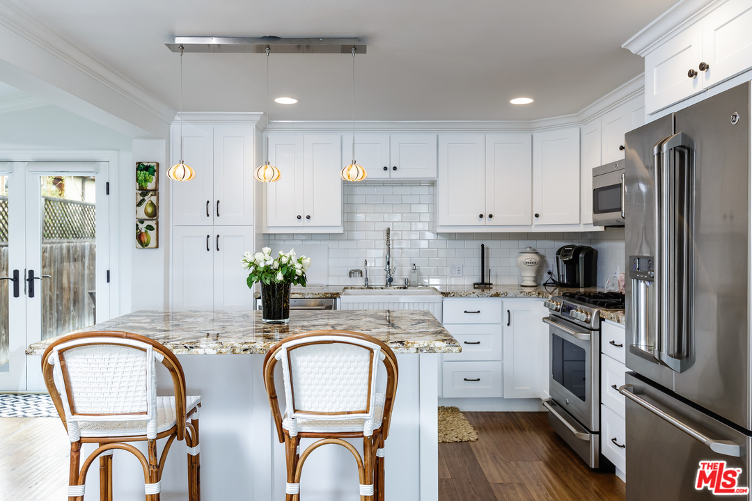 248 Paradise Cove Road Malibu, CA 90265 - Photo 5 of 35 a kitchen with stainless steel appliances granite countertop a stove top oven a sink a dining table and chairs with wooden floor