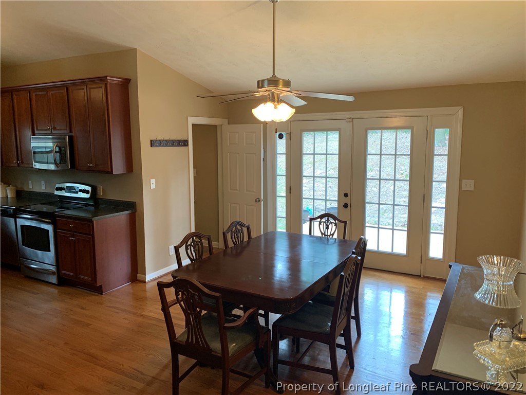 3629 Drayton Road Fayetteville, NC 28303 - Photo 7 of 31 a dining room with wooden floor a chandelier a wooden table and chairs