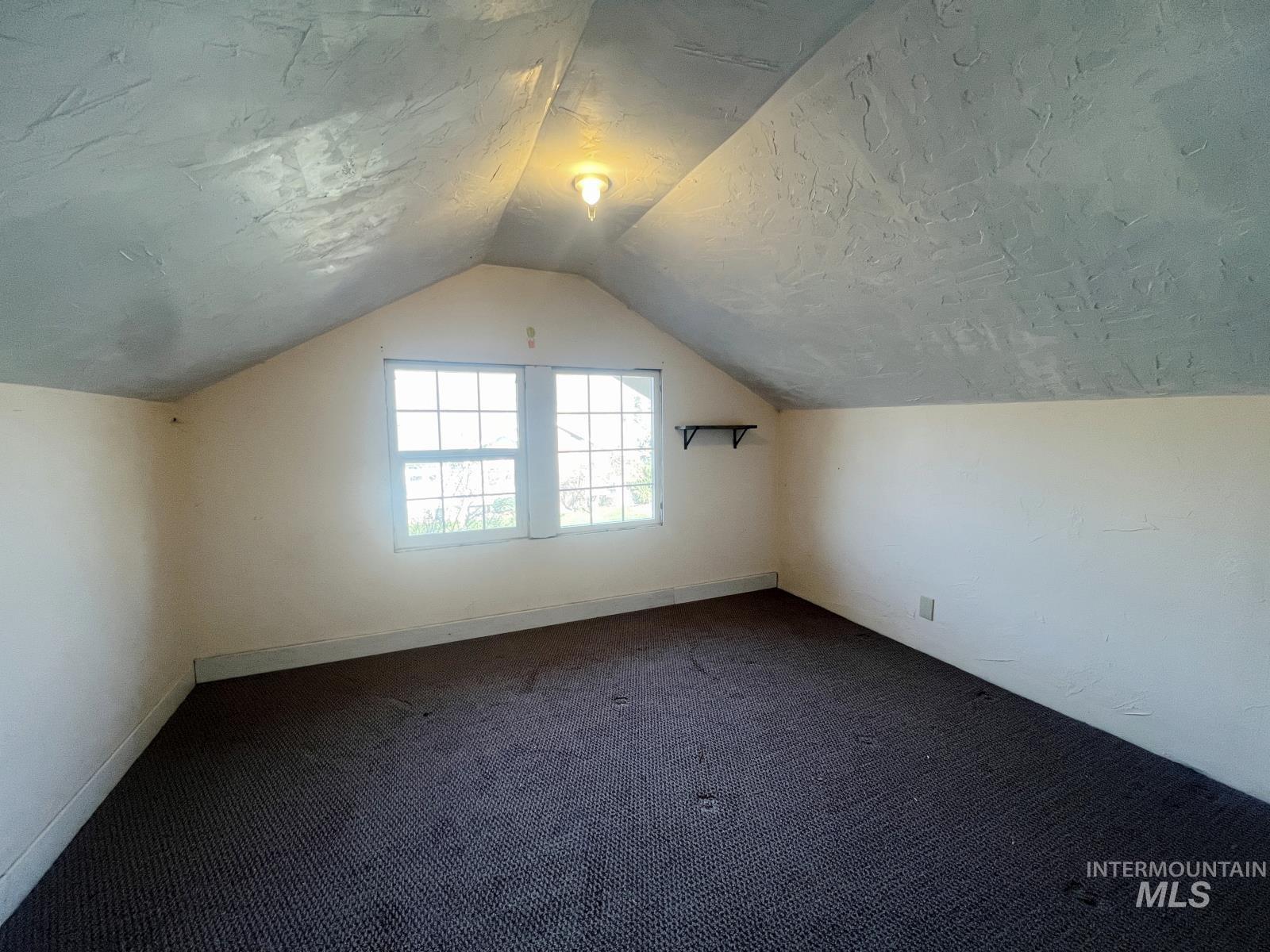 1002 9th Street Clarkston, WA 99403 - Photo 15 of 19 Bonus room with vaulted ceiling, dark carpet, and a textured ceiling