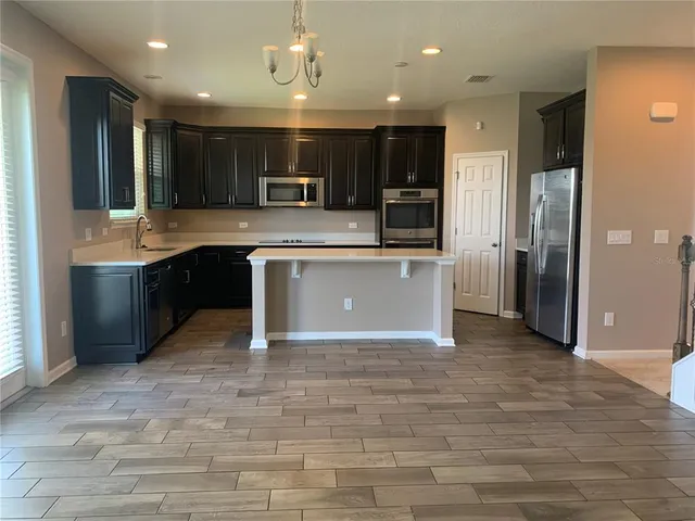 a kitchen with kitchen island a counter top space cabinets and stainless steel appliances