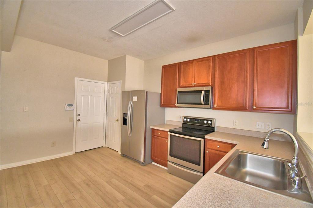 3151 Sinclair Street, Unit 104 Orlando, FL 32835 - Photo 18 of 64 a kitchen with granite countertop wooden cabinets stainless steel appliances and a sink