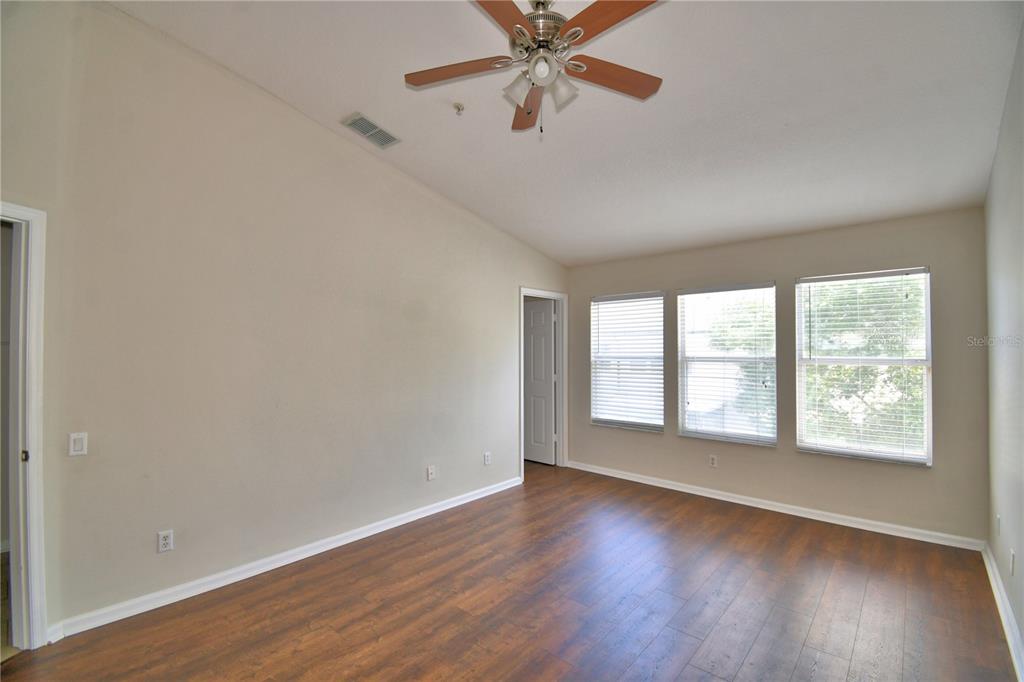 3151 Sinclair Street, Unit 104 Orlando, FL 32835 - Photo 22 of 64 an empty room with wooden floor chandelier fan and windows