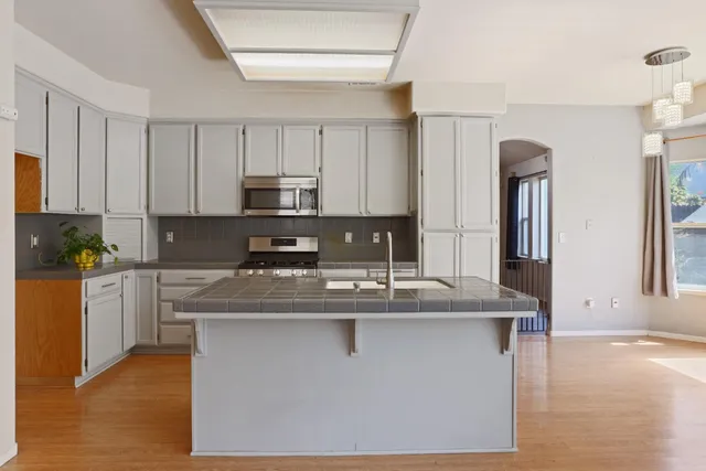 a kitchen with kitchen island granite countertop a sink cabinets and stainless steel appliances