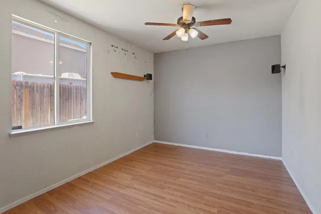 a view of an empty room with wooden floor and a window