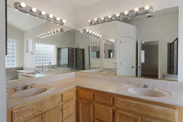 a spacious bathroom with a granite countertop sink a large mirror and shower
