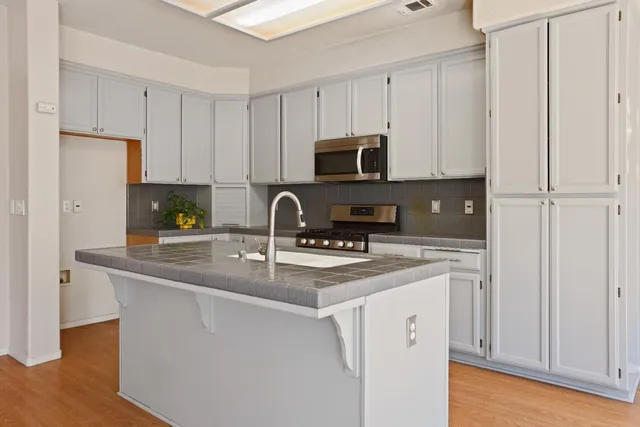 a kitchen with stainless steel appliances granite countertop a sink a stove a refrigerator and cabinets
