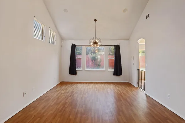 a view of an empty room with window and wooden floor