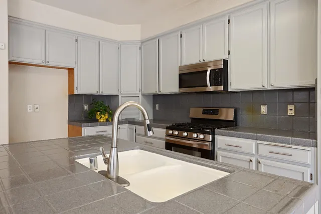 a kitchen with stainless steel appliances granite countertop a stove a sink and a microwave