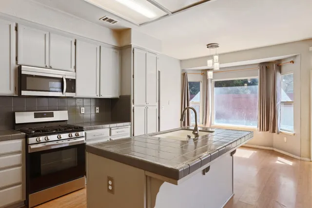 a kitchen with stainless steel appliances granite countertop a sink stove and cabinets