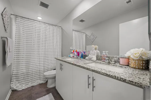 a bathroom with a granite countertop sink and a toilet