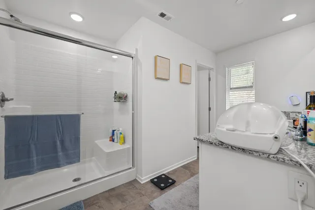 a bathroom with a granite countertop sink a mirror and shower