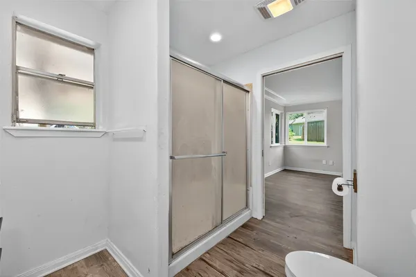 a view of an empty room with wooden floor and a bathroom