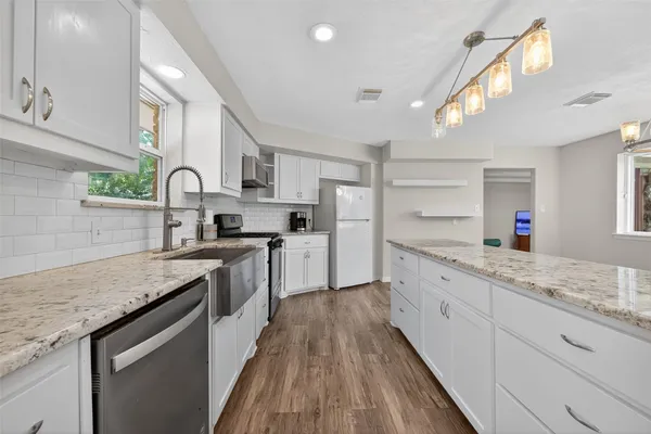 a kitchen with granite countertop stainless steel appliances cabinets a sink and a counter top space