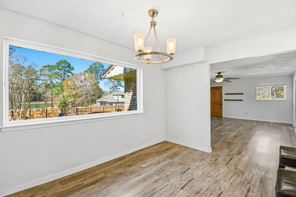 a view of a room with wooden floor chandelier and a window