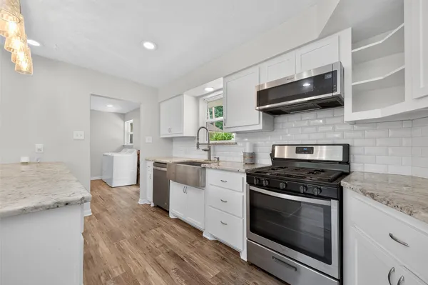 a kitchen with stainless steel appliances a stove microwave and sink