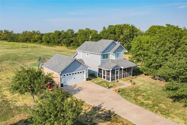 a white house with a big yard plants and large trees