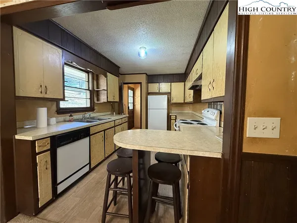 a kitchen with stainless steel appliances granite countertop a sink a stove a refrigerator with a dining table and chairs