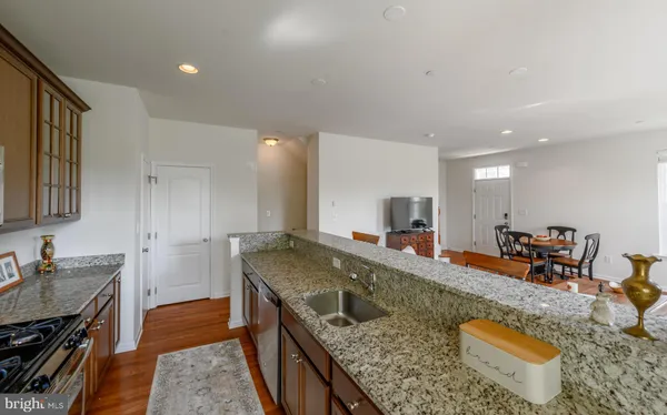 a kitchen with stainless steel appliances granite countertop a sink a stove and a wooden cabinets