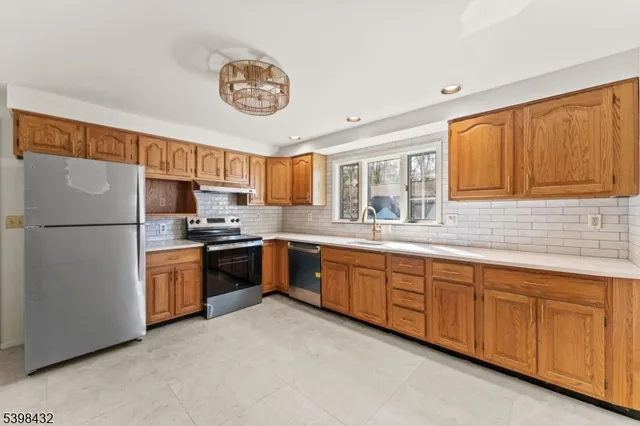 a kitchen with stainless steel appliances granite countertop a refrigerator a stove a sink and a cabinets