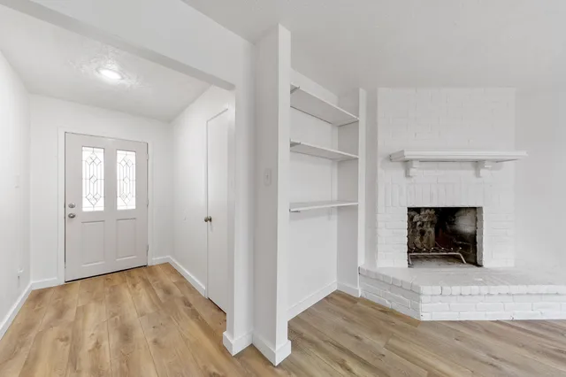 a view of empty room with wooden floor and fireplace