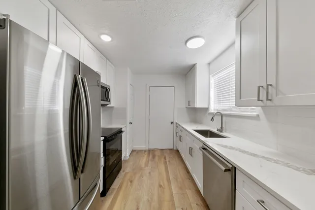 a kitchen with refrigerator a sink and wooden floor