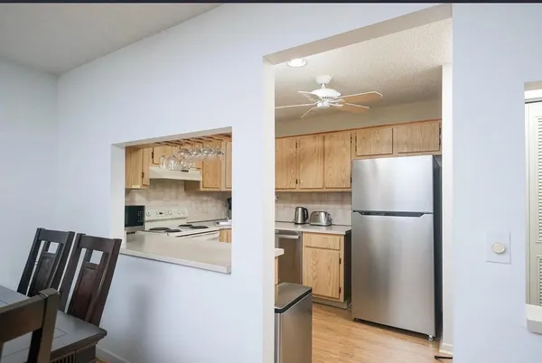 a kitchen with stainless steel appliances a refrigerator a stove a dining table and chairs