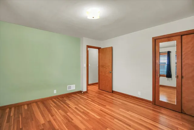 an empty room with wooden floor and closet