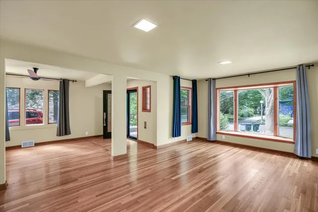 a view of an empty room with wooden floor and a window