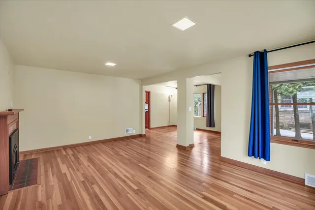 a view of an empty room with wooden floor and a window