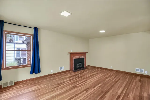 a view of empty room with wooden floor and fireplace