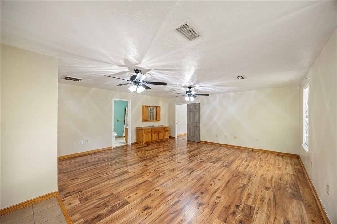 655 Charton Road Morrilton, AR 72110 - Photo 17 of 49 Spacious interior room featuring wood-finish flooring, light neutral walls, and multiple ceiling fans