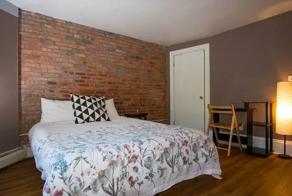 a bedroom with a bed and a chair with the wooden floor