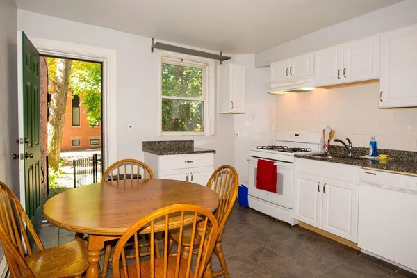 a kitchen with granite countertop a stove a sink a dining table and chairs