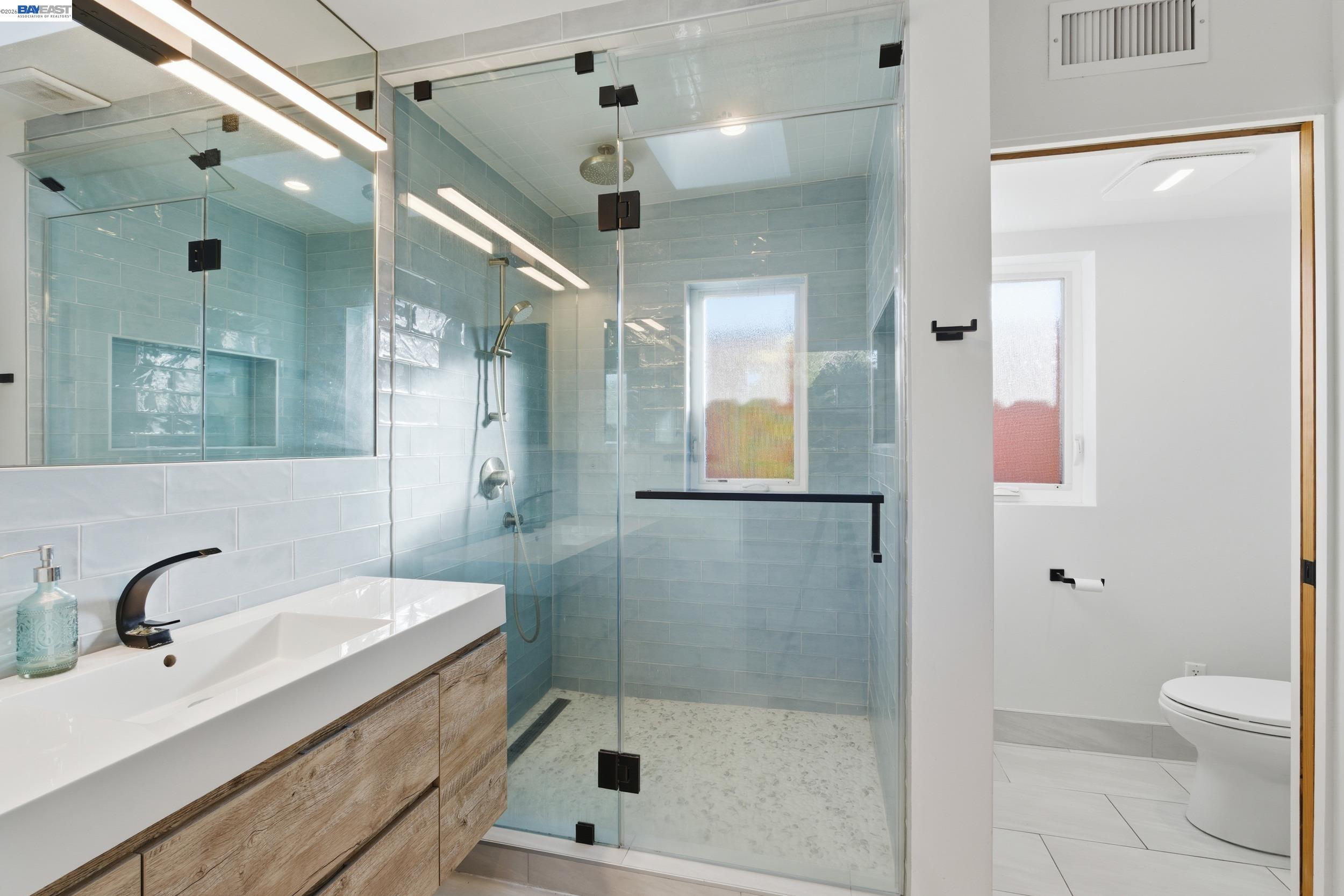 820 46th Street Oakland, CA 94608 - Photo 12 of 34 a bathroom with a shower sink vanity and mirror
