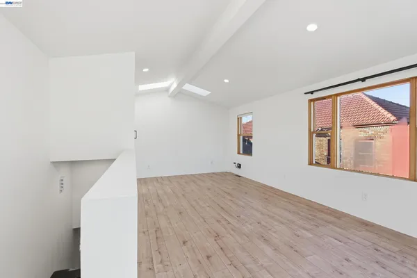 a view of an empty room with a window and wooden floor