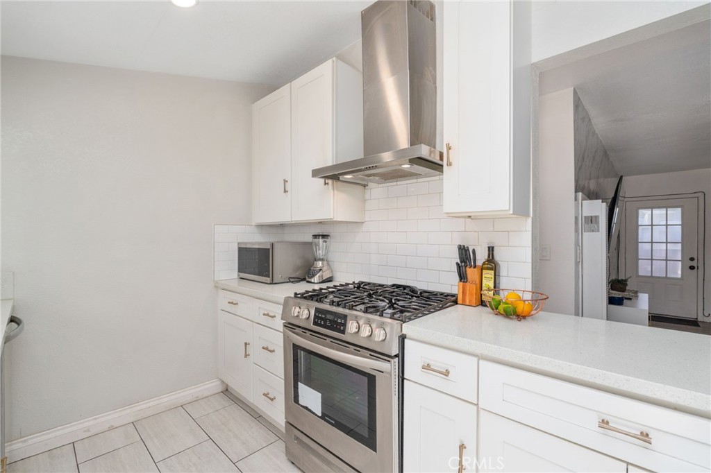411 South Hewes Street Orange, CA 92869 - Photo 12 of 37 a kitchen with stainless steel appliances a stove a sink and white cabinets