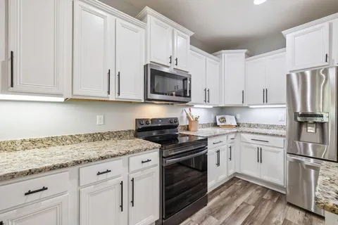 a kitchen with granite countertop white cabinets and stainless steel appliances