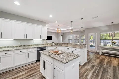 a large kitchen with granite countertop a island a sink stainless steel appliances and white cabinets